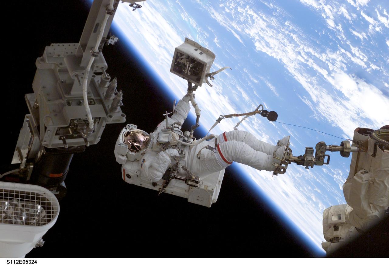 STS112-E-5324 (12 October 2002) --- Astronaut David A. Wolf, STS-112 mission specialist, his feet secured to a foot restraint on the end of the Space Station Remote Manipulator System (SSRMS) or Canadarm2, participates in a six hour, four minute session of extravehicular activity (EVA) on which he was joined by astronaut Piers J. Sellers (out of frame).