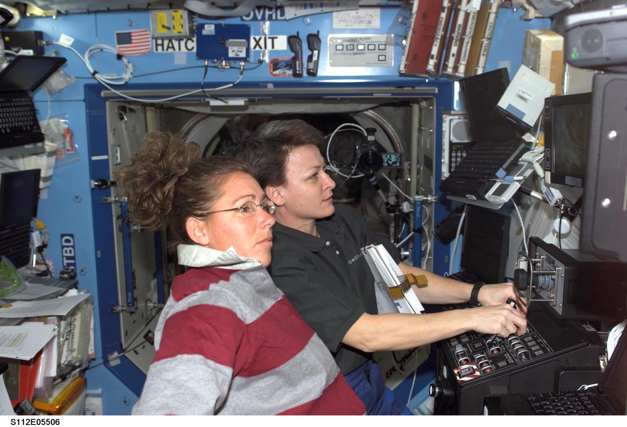 STS112-E-05506 (14 October 2002) --- Astronauts Peggy A. Whitson (background), Expedition Five flight engineer, and Sandra H. Magnus, STS-112 mission specialist, work the controls of the Canadarm2 from inside the Destiny laboratory on the International Space Station (ISS). Whitson and Magnus used the station&#0146;s robotic arm in support of the third session of extravehicular activity (EVA) for the STS-112 mission.