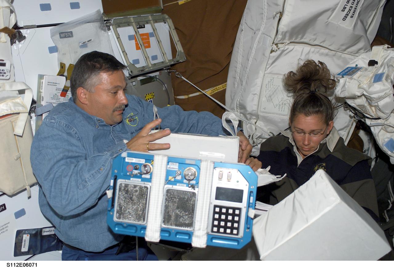 STS112-E-06071 (15 October 2002) --- Cosmonaut Fyodor N. Yurchikhin (left) and astronaut Sandra H. Magnus, STS-112 mission specialists, work on the middeck of the Space Shuttle Atlantis. Yurchikhin represents Rosaviakosmos.