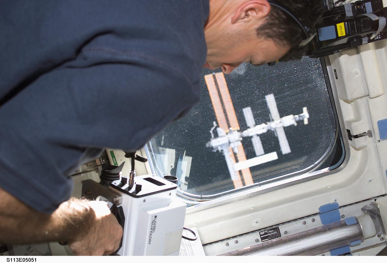 STS113-E-05051 (25 November 2002) --- Astronaut Michael E. Lopez-Alegria, STS-113 mission specialist, uses a laser ranging device on the aft flight deck of the Space Shuttle Endeavour. This instrument is a regularly called-on tool during rendezvous operations with the International Space Station (ISS). The station is visible through an overhead window. Endeavour docked with the station at 3:59 p.m. (CST) on November 25, 2002.
