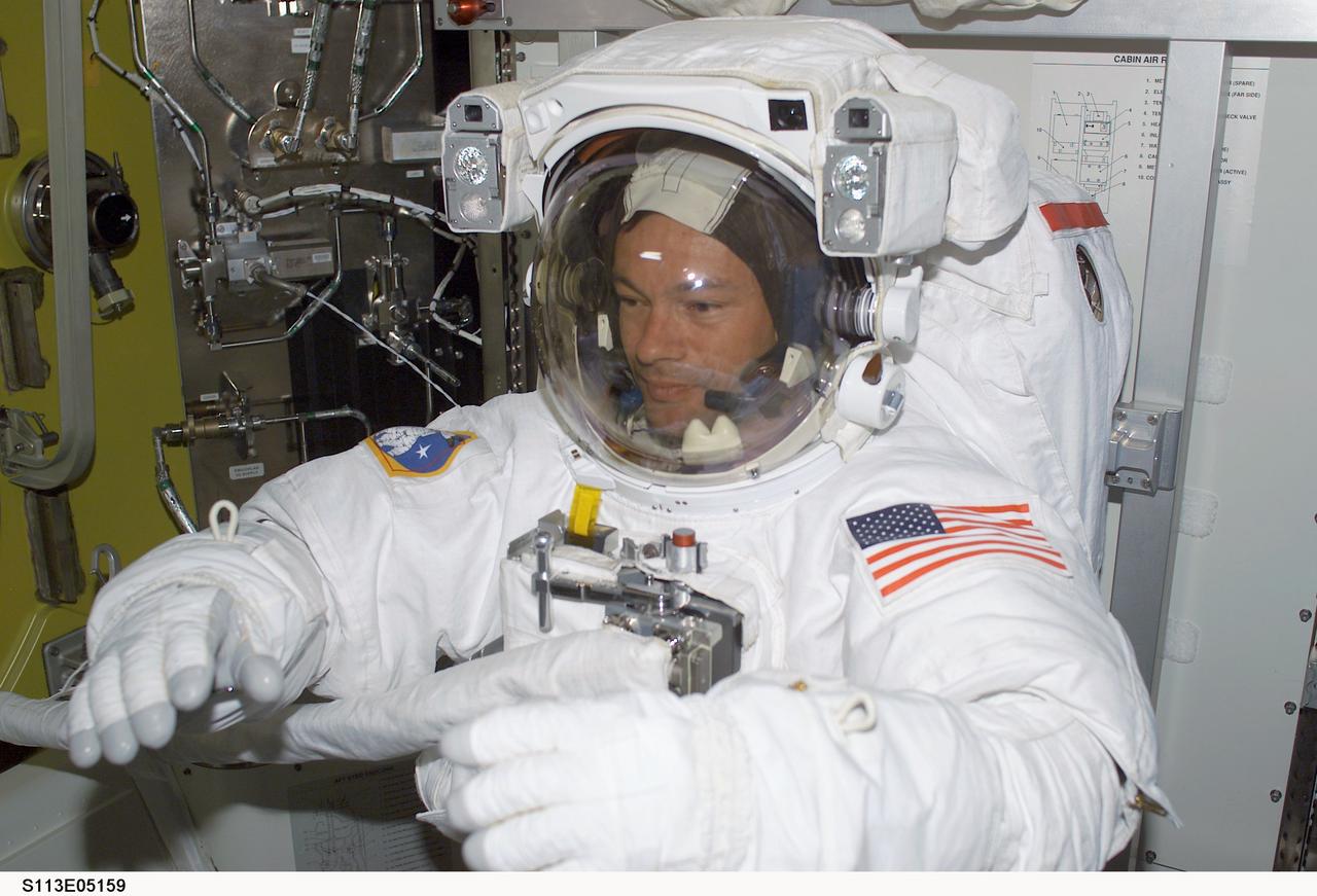 STS113-E-05159 (26 November 2002) ---  Astronaut Michael E. Lopez-Alegria   completes final touches on his extravehicular mobility unit (EMU) space suit aboard the International Space Station (ISS). Moments later, astronauts Lopez-Alegria and John B. Herrington went on to begin the first of three spacewalks to perform work on the station. With the assistance of the rest of the shuttle and station crewmembers who worked inside the shirt sleeve environments of the two docked spacecraft, the two mission specialists  completed the six hour, 45-minute spacewalk and successfully hooked up connections  between the Port One (P1) truss and the rest of the station.