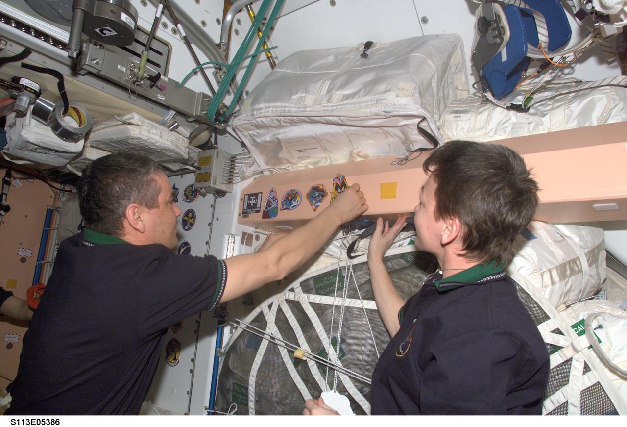 STS113-E-05386 (2 December 2002) --- Cosmonaut Valery G. Korzun, Expedition Five mission commander, adds the Expedition Five crew patch to the growing collection of those representing Expedition crews who have worked on the International Space Station (ISS). A location in the Unity node serves as one of the traditional posting sites for the patches. Astronaut Peggy A. Whitson, NASA ISS science officer, is to the right of Korzun, who represents Rosaviakosmos.