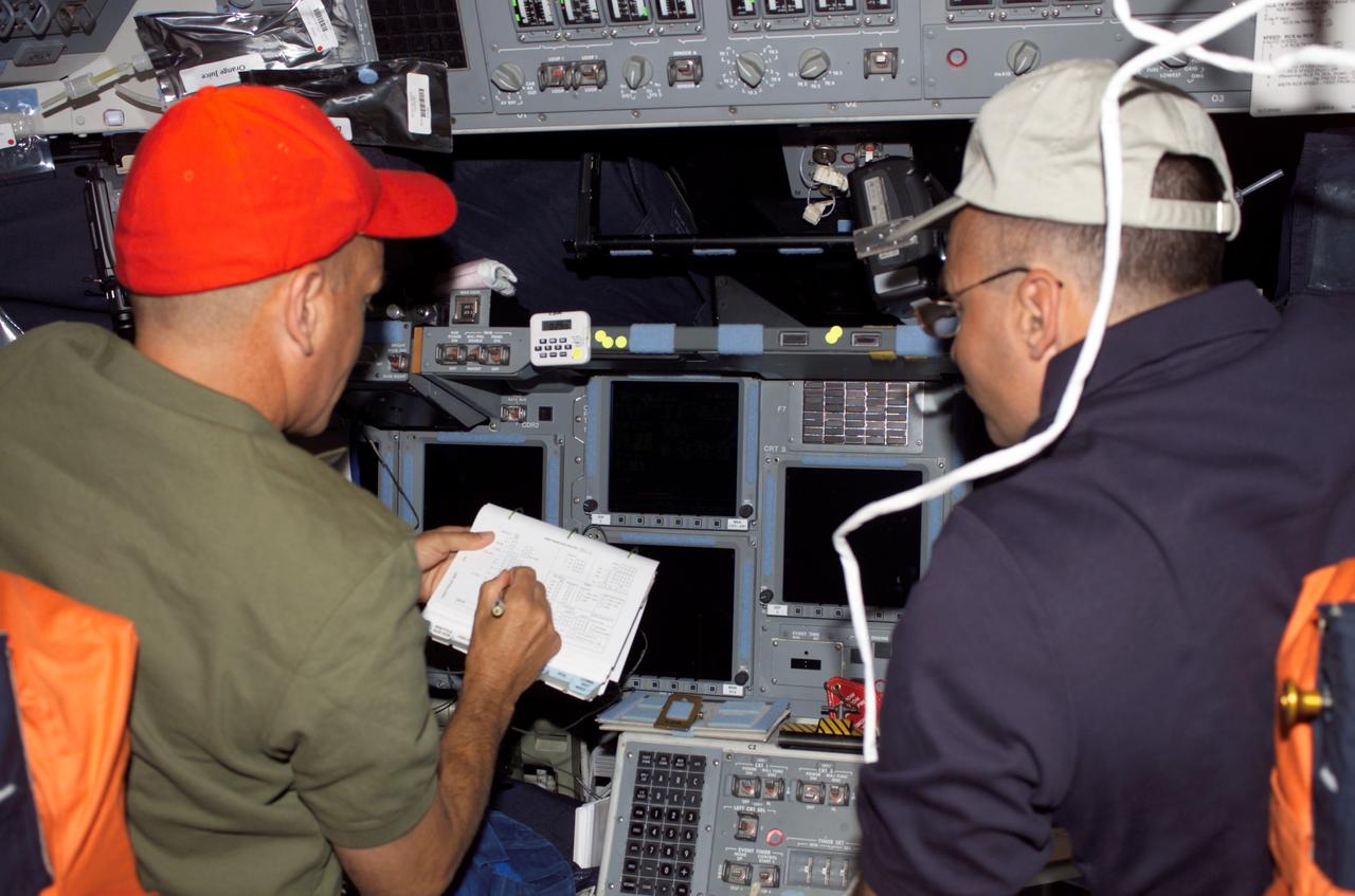 S117-E-06625 (9 June 2007) --- Astronauts Rick Sturckow (left) and Lee Archambault, STS-117 commander and pilot, respectively, look over procedures checklists on the flight deck of Space Shuttle Atlantis.