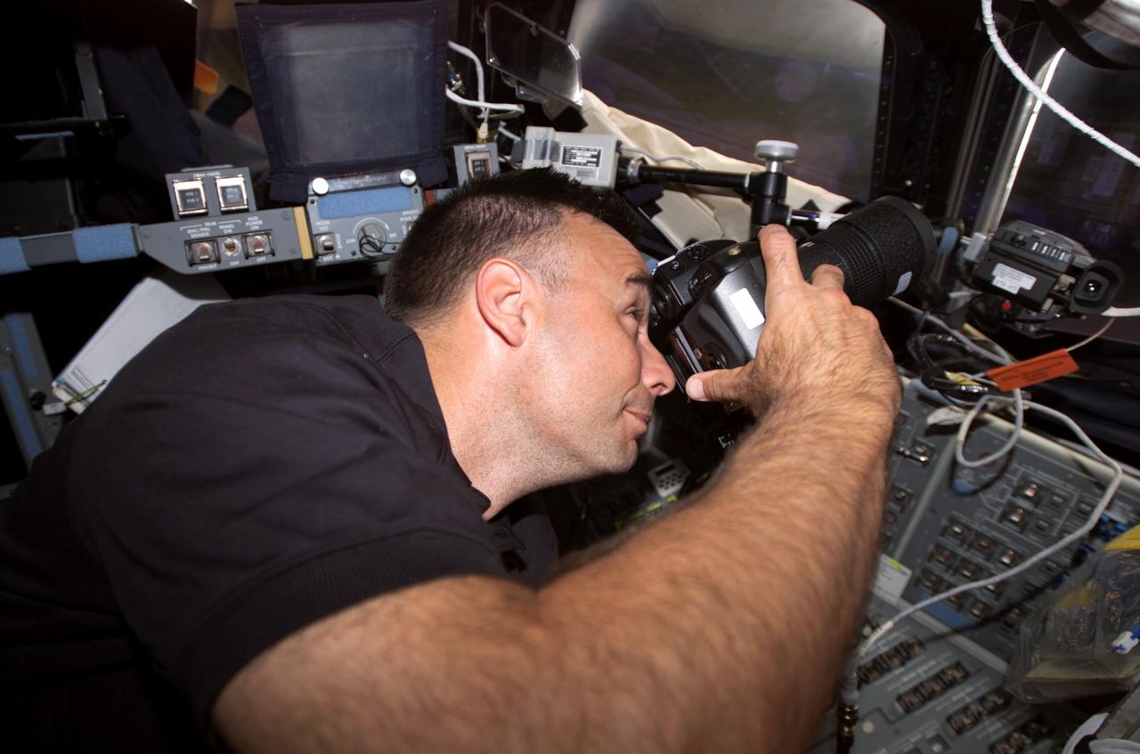 S117-E-07206 (14 June 2007 ) --- Astronaut Lee Archambault, pilot, aims a camera through windows on the flight deck of the Space Shuttle Atlantis about half way through the STS-117 mission.