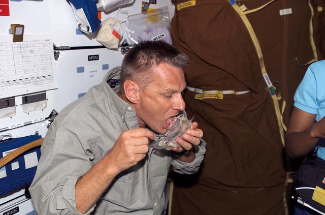 NASA image: Sellers eats from a food container in the MDK during STS-121