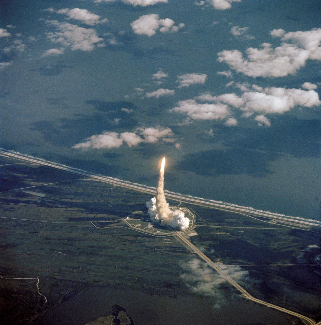 STS027-S-006 (2 Dec. 1988) --- A good portion of the Kennedy Space Center launch complex 39 and the Atlantic Ocean form the backdrop for the beginning stages of Atlantis' return trip to space. The scene was captured with a hand-held 70mm camera aimed through the windows of a NASA shuttle training aircraft piloted by astronaut Daniel C. Brandenstein, chief of Johnson Space Center?s astronaut office. Launch occurred at 9:30:34 a.m. (EST), Dec. 2, 1988. Photo credit: NASA