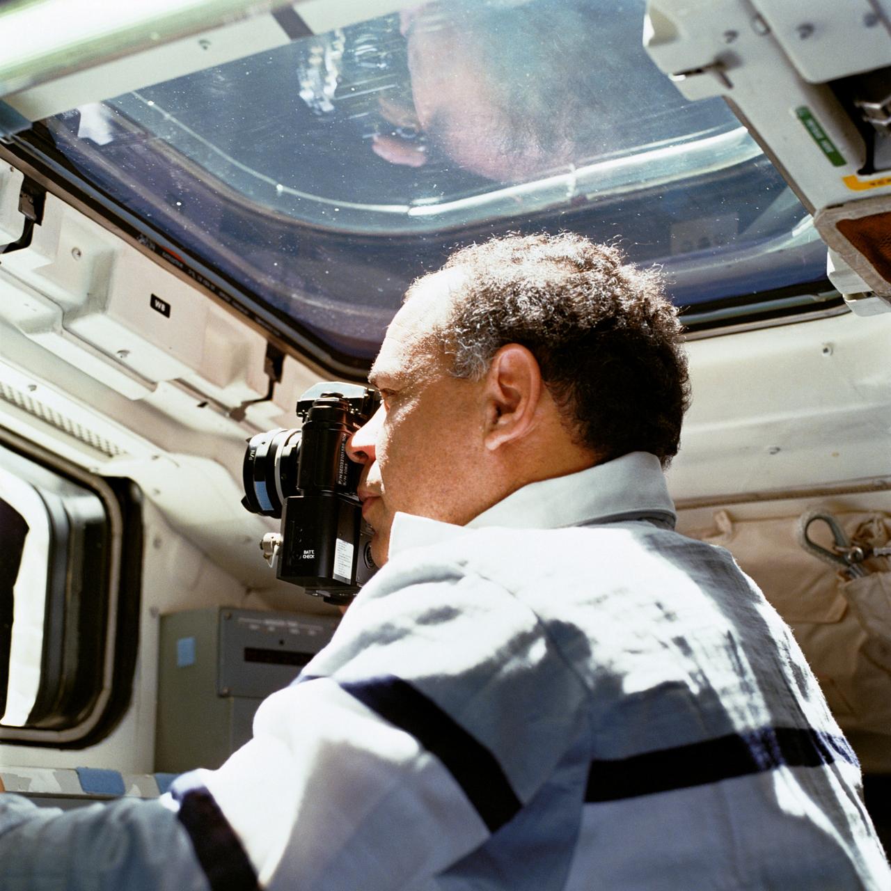 STS033-93-036 (22-27 Nov. 1989) --- Astronaut Frederick D. Gregory, STS-33 commander, aims a 35mm camera out an aft flight deck viewing window while onboard the Space Shuttle Discovery.