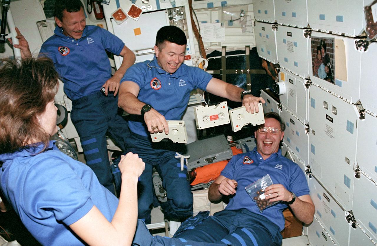 STS037-54-004 (5-11 April 1991) --- Four crew members have fun with weightlessness on the Space Shuttle Atlantis' middeck.  Astronaut Kenneth D. Cameron, pilot, performs a "quick hands" feat with three tape cassettes -- obviously a feat much more difficult on Earth. Looking on, left to right, are astronauts Linda M. Godwin, mission specialist; Steven R. Nagel, mission commander; and Jerry L. Ross, mission specialist.  Ross later used the microgravity environment to have some fun with the bag of malted milk balls in his hands. This 35mm frame was exposed by astronaut Jerome (Jay) Apt, mission specialist.  This was one of the visuals used by the crew members during their April 19 Post Flight Press Conference (PFPC) at the Johnson Space Center (JSC).