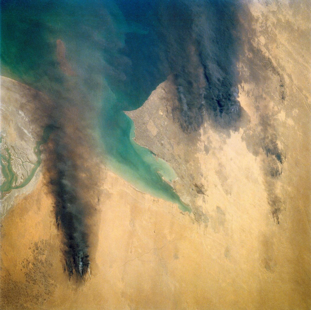 STS039-72-060 (28 April-6 May 1991) --- This view from the Earth-orbiting Space Shuttle Discovery shows the smoke from burning oil well fires, aftermath of Iraqi occupation.  Oil wells to the north of the Bay of Kuwait and just south of Kuwait City, on the south shore, can be seen burning out of control.  Compared with pictures of the same area shot during STS-37 (April 1991), this frame shows a complete shift of winds, with much of the smoke blowing eastward over the Gulf.  The STS-37 scenes showed lengthy southward-blowing sheets of smoke toward Saudi Arabia.  In this view, the Gulf island Faylakah Awhah is barely visible through the smoke.