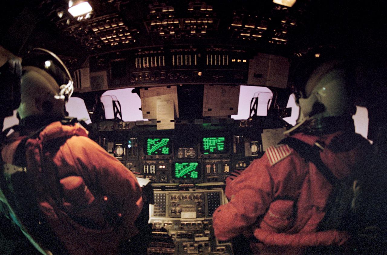 STS042-45-033 (30 Jan. 1992) --- Astronauts Ronald J. Grabe (left) and Stephen S. Oswald man the commander and pilot stations, respectively, during the entry phase of the STS-42 mission. The pink glow through the front windows telltale of friction caused heat encountered upon passing through Earth's atmosphere on the return trip home.