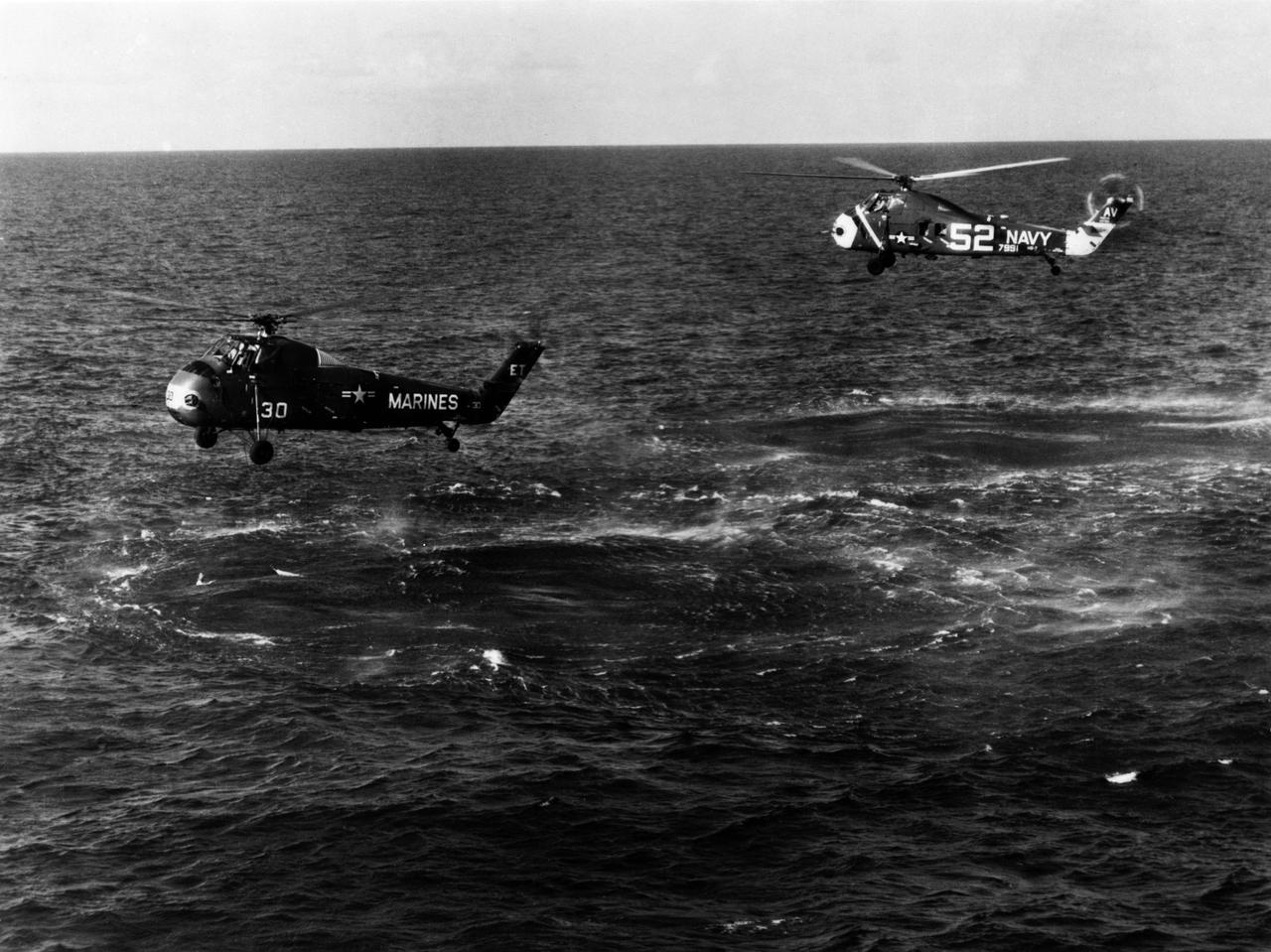 S61-02820 (21 July 1961) --- Attempted recovery of Mercury spacecraft at end of the Mercury-Redstone 4 (MR-4) mission. View shows the Marine helicopter pulled almost to the waters surface by the weight of the capsule, which filled with water. It eventually had to abandon its recovery attempts. Behind the Marine helicopter, a Navy helicopter prepares to assist. Photo credit: NASA