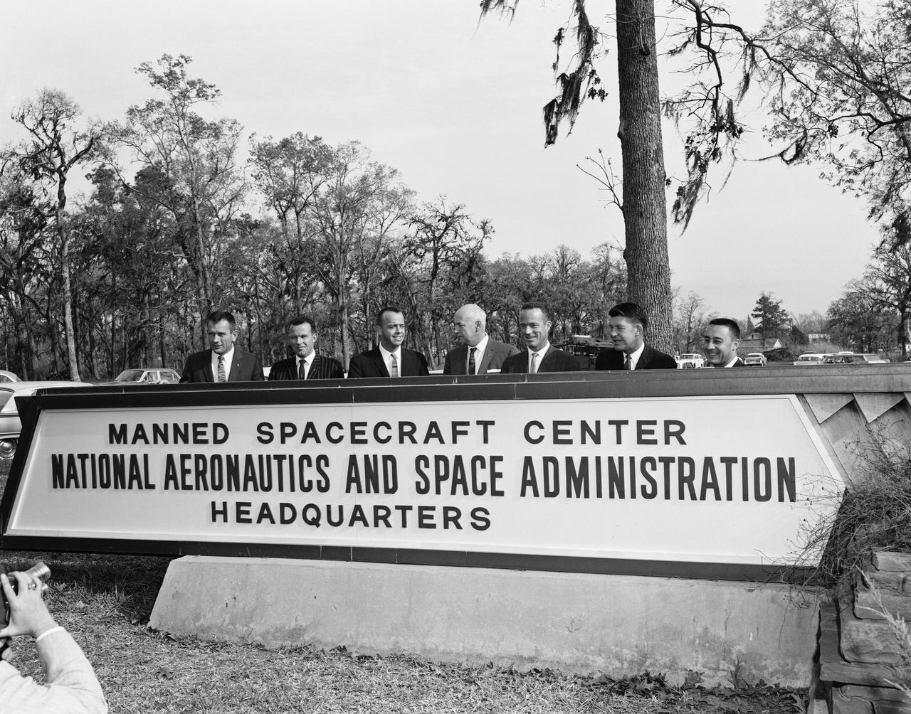 Astronaut Alan Shepard with Gilruth, and Astronauts Slayton, Cooper, Carpenter, Schirra, Grissom around the Manned Spacecraft Center (MSC) sign at the Farnsworth-Chambers Bldg.               FARNSWORTH-CHAMBERS BLDG., HOUSTON, TX                B&W