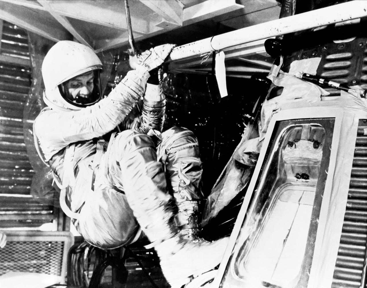 S62-00993 (1962) --- Astronaut John H. Glenn Jr., pilot of the Mercury-Atlas 6 (MA-6) mission, practices insertion into the Mercury "Friendship 7" spacecraft during MA-6 preflight training activity at Cape Canaveral, Florida. He is wearing the full pressure suit and helmet. Photo credit: NASA