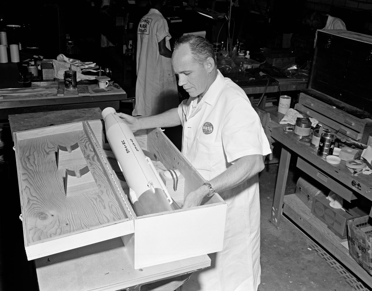 View of NASA Technical Services personnel packing model of rocket in the Canada Dry Bldg.