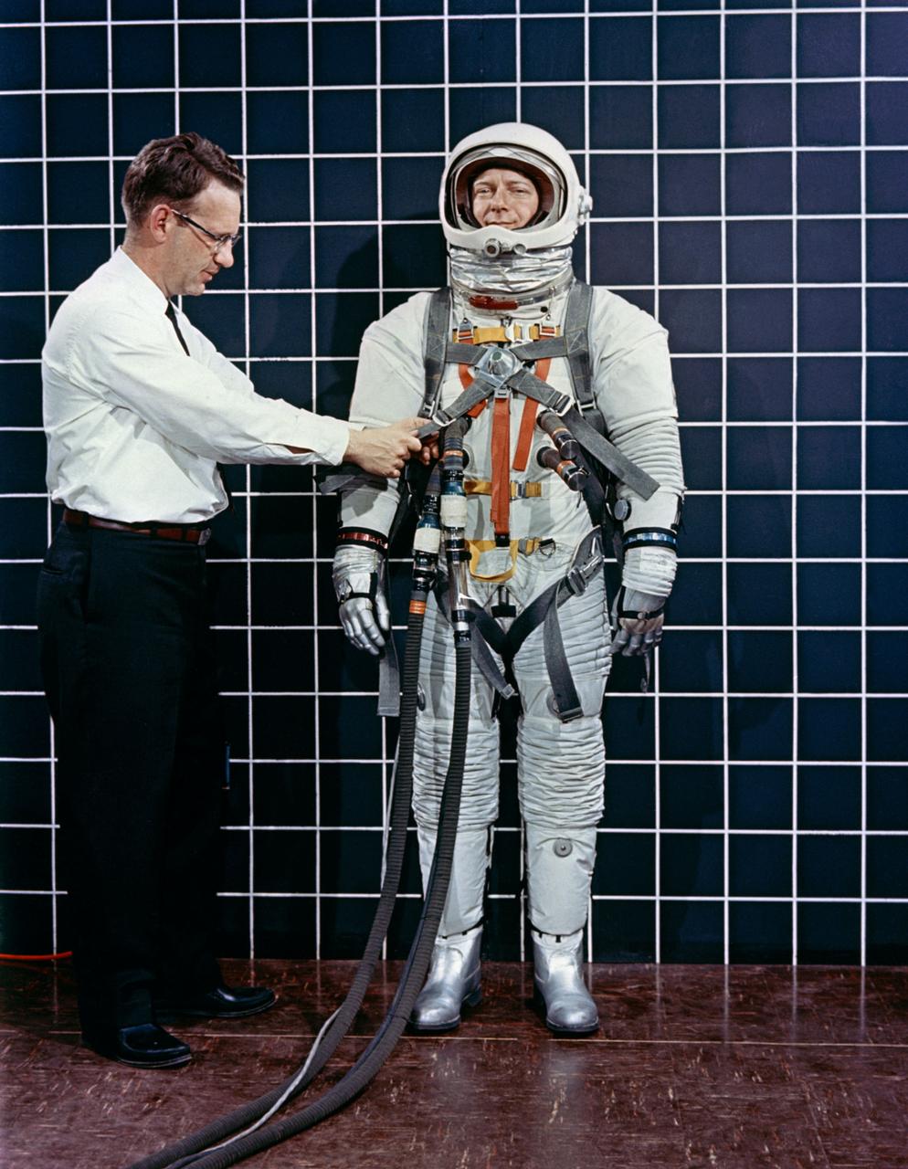 Engineer Bill Peterson fits test pilot Bob Smyth in spacesuit A-3H-024 with the LEM Astronaut restraint harness during suit evaluation study.