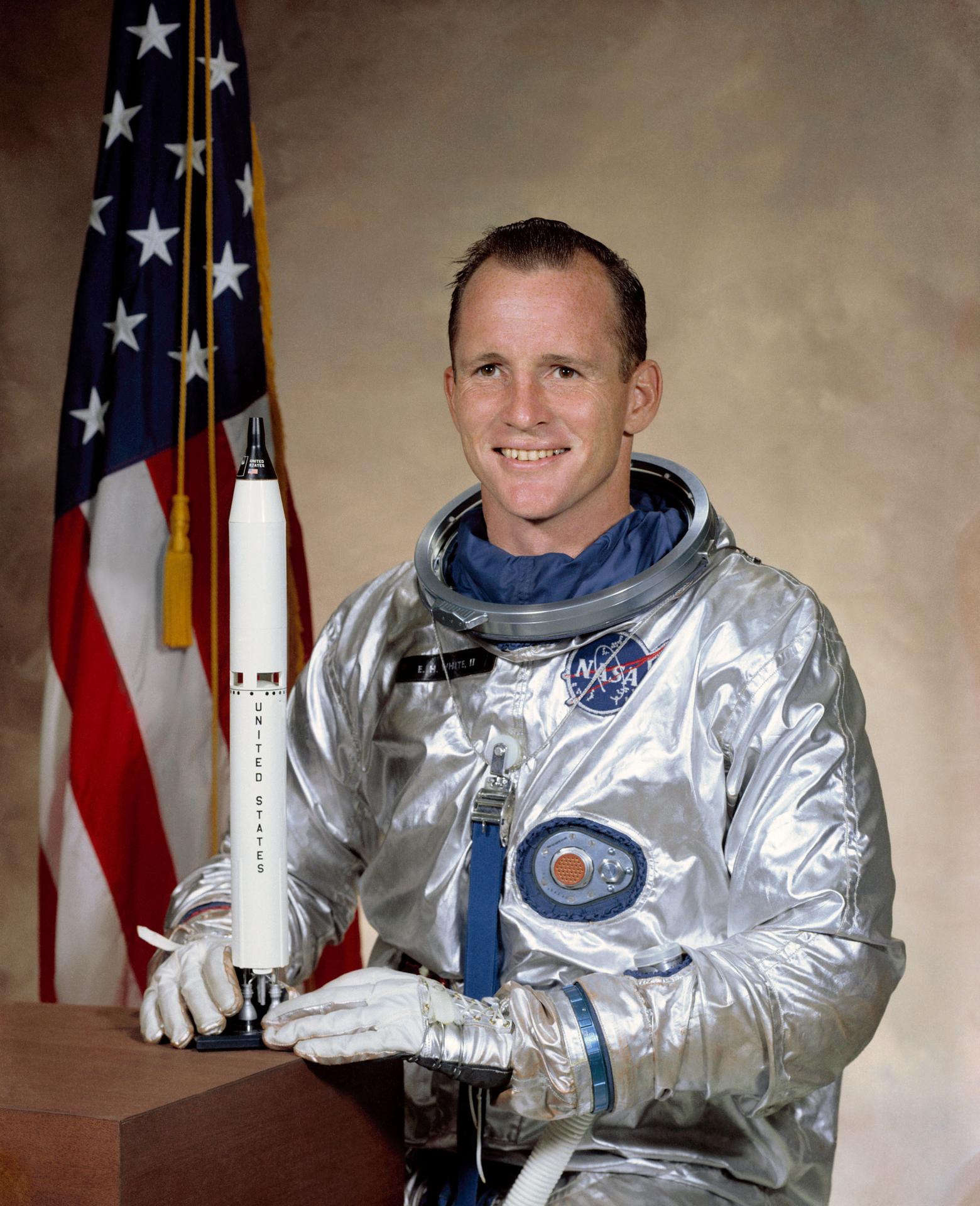 Astronaut Edward H. White II posing in front of an American flag