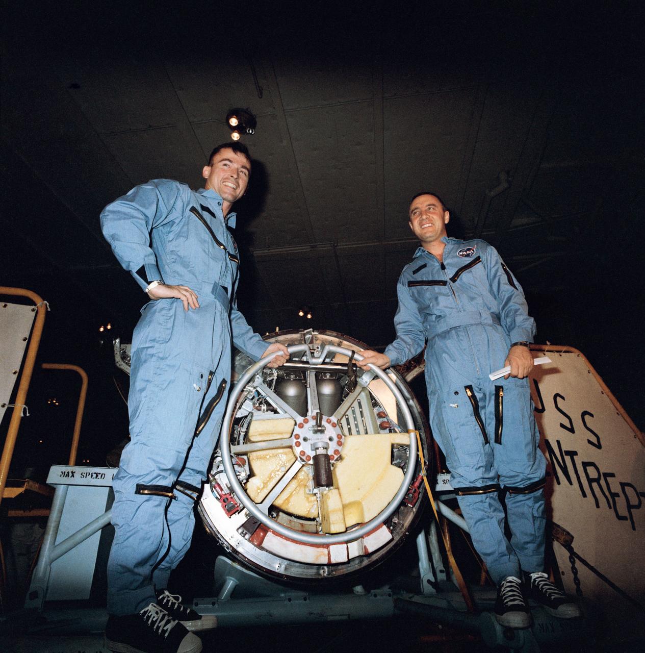 S65-18713 (23 March 1965) --- Astronauts John W. Young (left) and Virgil I. Grissom are shown during their first inspection of the Gemini 3 spacecraft aboard the USS Intrepid following their successful Gemini-Titan 3 flight. Photo credit: NASA or National Aeronautics and Space Administration