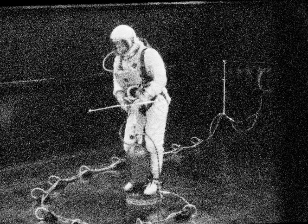 S65-19505 (28 May 1965) --- Astronaut Edward H. White II, pilot for the Gemini-Titan 4 prime crew, is pictured during an extravehicular exercise in the Building 4 laboratory at the Manned Spacecraft Center in Houston, Texas. White is controlling about the yaw (vertical) axis while translating. He stands on a Balance Extravehicular Training Aircraft which is separated from the level steel floor by a .001th-inch cushion of air. In his right hand White holds a zero-gravity integral propulsion unit which is a self-maneuvering device used by an astronaut in a zero-gravity environment. This condition is simulated in this training exercise. White's spacesuit is pressurized to create a realistic training condition. The simulated umbilical line is floated on air with the aid of eleven small air pads.