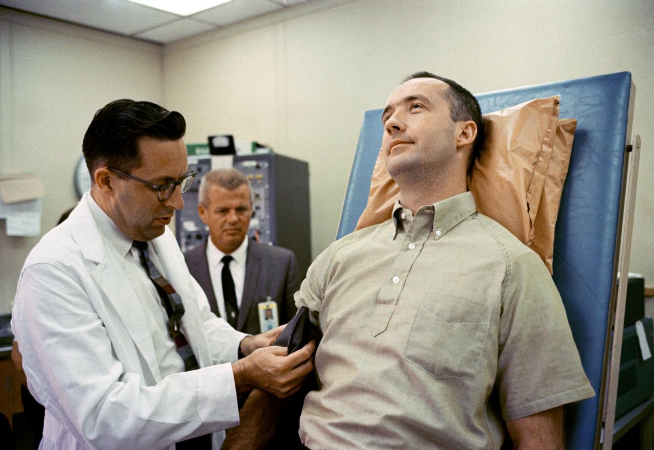 S65-19524 (1 June 1965) --- Dr. Charles A. Berry, chief of Center Medical Programs, MSC, Houston, Texas, prepares to check the blood pressure of astronaut James A. McDivitt, command pilot for the Gemini-Titan 4 spaceflight. McDivitt is on the tilt table at the Aero Medical Area, MSC, Merritt Island, where he and astronaut Edward H. White II (out of frame), GT-4 pilot, underwent preflight physicals in preparation for the four-day, 62-revolution spaceflight. The two astronauts were declared in top physical condition. In the background is Dr. Gordon Benson, NASA physician at Cape Kennedy.