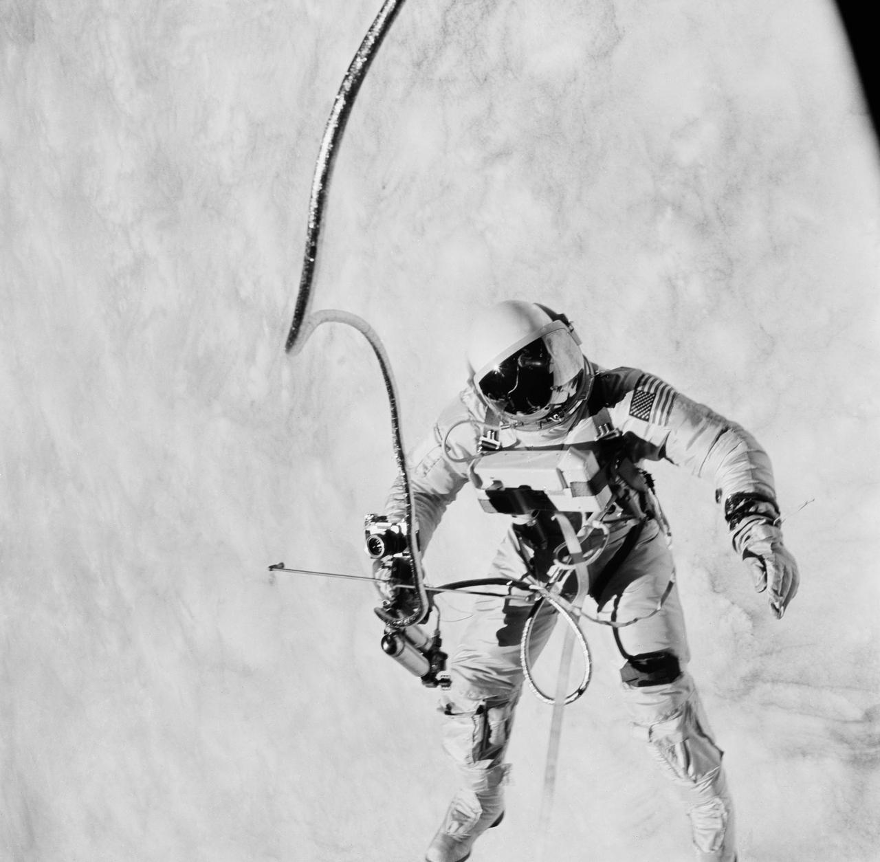 S65-30272 (3 June 1965) --- Astronaut Edward H. White II, pilot on the Gemini-Titan IV (GT-4) spaceflight, floats in the zero gravity of space outside the Gemini IV spacecraft. His face is covered by a shaded visor to protect him from the unfiltered rays of the sun. White became the first American astronaut to walk in space. He remained outside the spacecraft for 21 minutes during the third revolution of the Gemini IV mission. He wears a specially designed spacesuit for the EVA. His right hand is holding the Hand-Held Self-Maneuvering Unit (HHSMU), with which he controlled his movements while in space, and a camera is attached to the HHSMU. He was attached to the spacecraft by a 25-feet umbilical line and a 23-feet tether line, both wrapped together with gold tape to form one cord. He wears an emergency oxygen supply check pack. Astronaut James A. McDivitt is command pilot for the GT-4 mission. The mission was a four-day, 62-revolution flight, during which McDivitt and White performed a series of scientific and engineering experiments. (This image is black and white) Photo credit: NASA    EDITOR?S NOTE: Astronaut Edward H. White II died in the Apollo/Saturn 204 fire at Cape Kennedy, Florida, on Jan. 27, 1967.