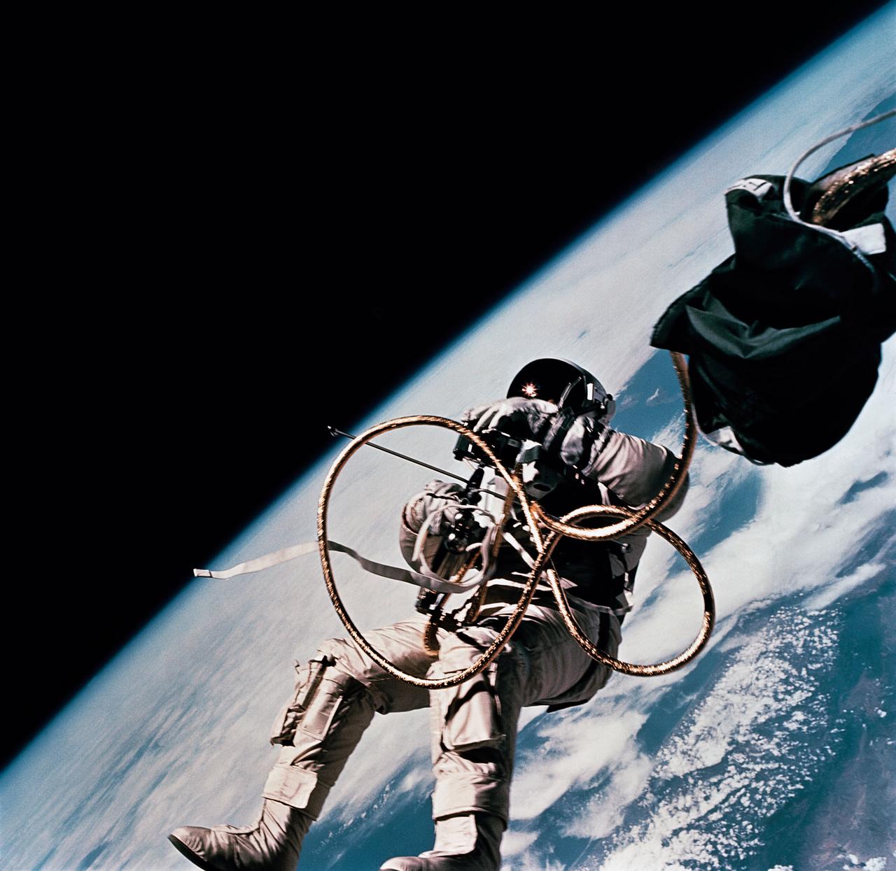 S65-30430 (3 June 1965) --- Astronaut Edward H. White II, pilot on the Gemini-Titan 4 spaceflight, is shown during his egress from the spacecraft. His face is covered by a shaded visor to protect him from the unfiltered rays of the sun. White became the first American astronaut to walk in space. He remained outside the spacecraft for 21 minutes during the third revolution of the Gemini-4 mission. He wears a specially designed spacesuit for the extravehicular activity (EVA). In his right hand, he carries a Hand-Held Self-Maneuvering Unit (HHSMU) with which he controlled his movements while in space. He was attached to the spacecraft by a 25-feet umbilical line and a 23-feet tether line, both wrapped together with gold tape to form one cord. He wears an emergency oxygen supply chest pack. Astronaut James A. McDivitt is command pilot for the Gemini-4 mission. Photo credit: NASA    EDITOR'S NOTE: Astronaut Edward H. White II died in the Apollo/Saturn 204 fire at Cape Kennedy on Jan. 27, 1967.
