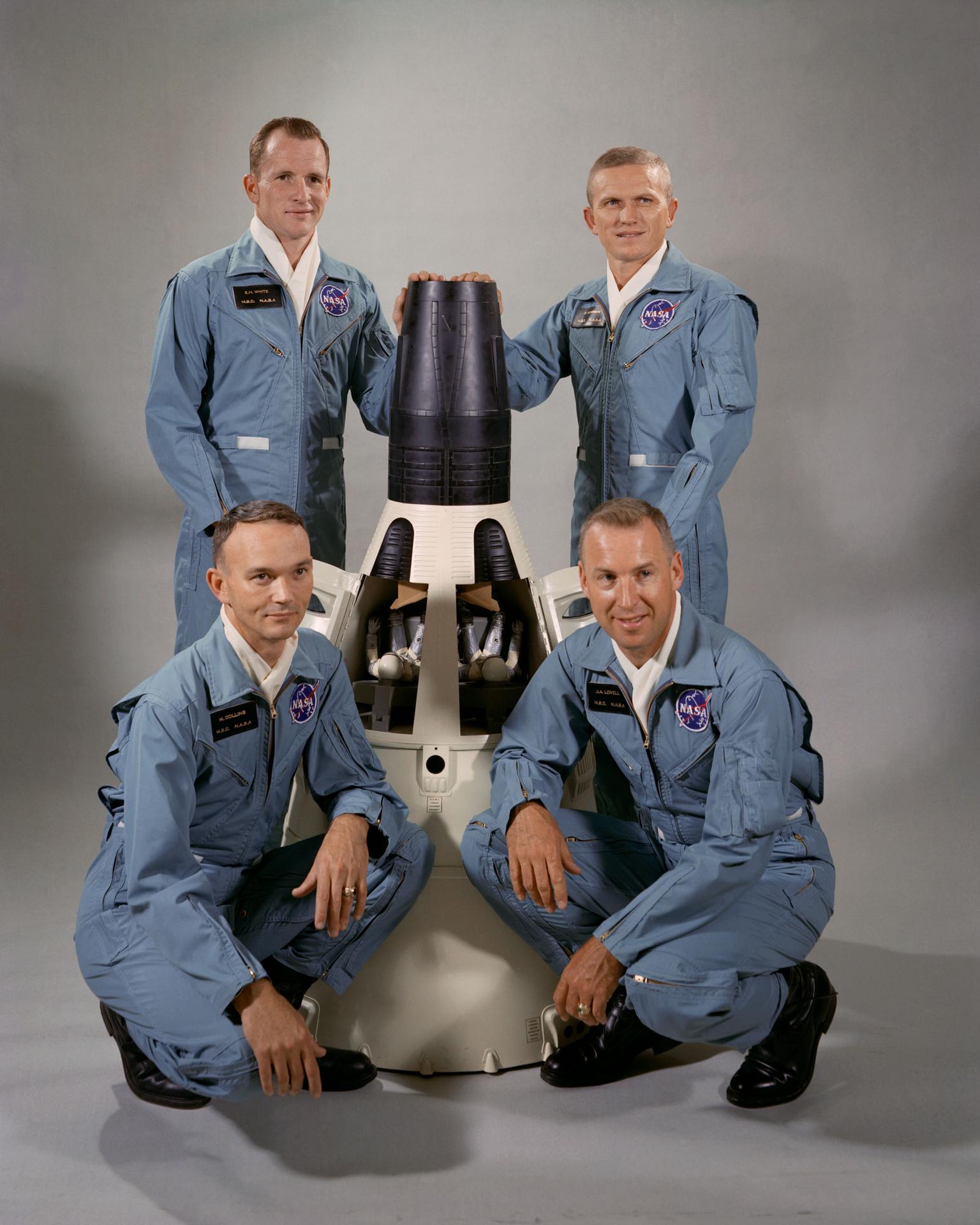 Frank F. Borman posing for portrait in blue jumpsuit with model shuttle