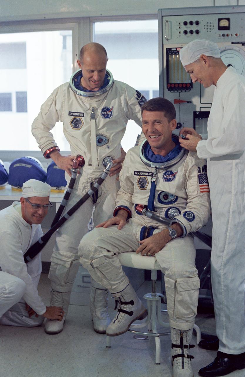 S65-56190 (20 Oct. 1965) --- Astronauts Walter M. Schirra Jr. (seated), command pilot; and Thomas P. Stafford, pilot, the prime crew of NASA's Gemini-Titan-Agena 6 space mission, go through suiting up exercises in preparation for their forthcoming flight. The suit technicians are James Garrepy (left) and Joe Schmitt. Photo credit: NASA or National Aeronautics and Space Administration