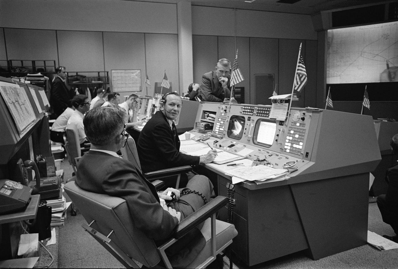 S65-62938 (16 Dec. 1965) --- John D. Hodge (foreground), Christopher C. Kraft Jr. (center) and Eugene F. Kranz discuss recovery operations for the Gemini-6 spacecraft in the Mission Control Center (MCC) at the Manned Spacecraft Center (MSC) in Houston, Texas. The event was monitored via live television in MCC. Photo credit: NASA or National Aeronautics and Space Administration