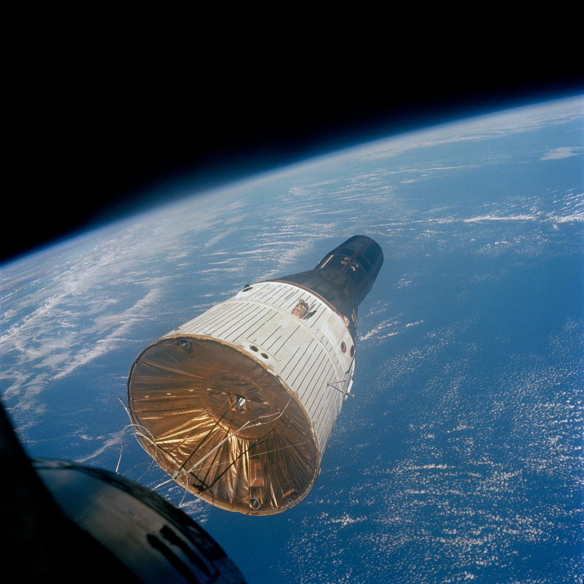 View of the Gemini 7 spacecraft in orbit above the Earth as seen from the Gemini 6 spacecraft.