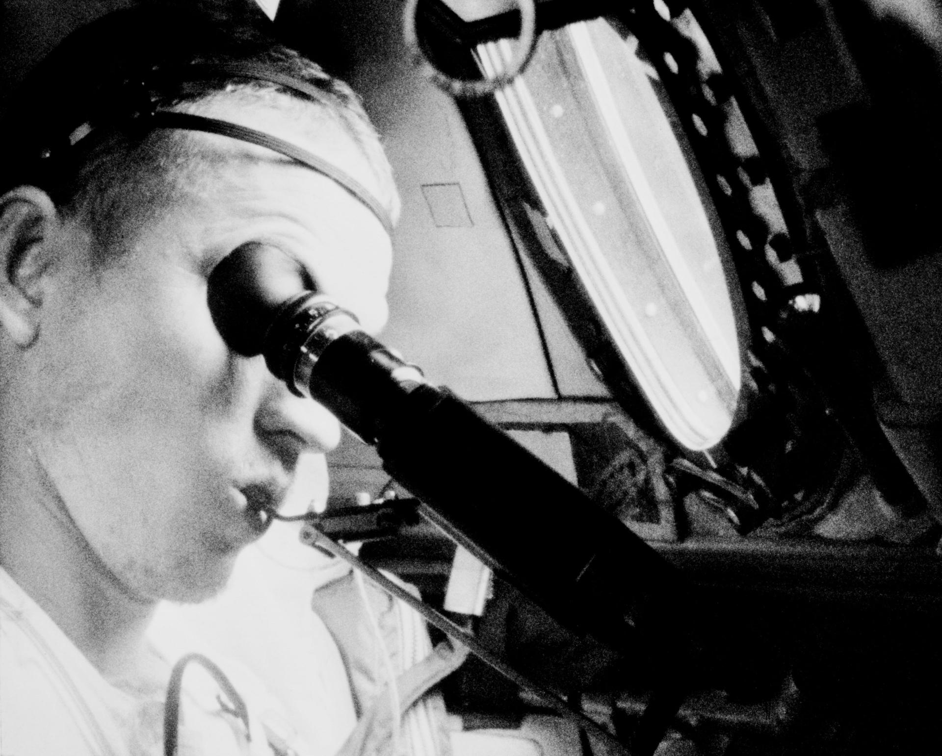 Frank Borman uses the visual acuity device and portable mouth thermometer in space during the Gemini VII mission