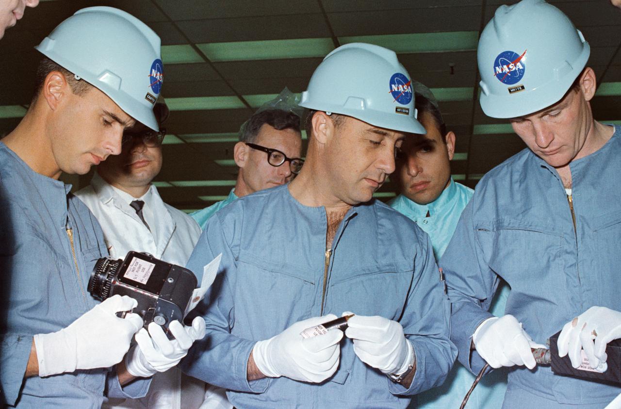 The members of the prime crew of the first manned Apollo space flight Apollo/Saturn 204 (AS-204) inspect spacecraft equipment during a tour of North American Aviation's (NAA) Downey facility.  In the foreground, left to right, are astronauts Roger B. Chaffee, Virgil I. Grissom, and Edward H. White, II.  NAA engineers and technicians are in the background.        NORTH AMERICAN AVIATION, INC., DOWNEY, CA       B&W