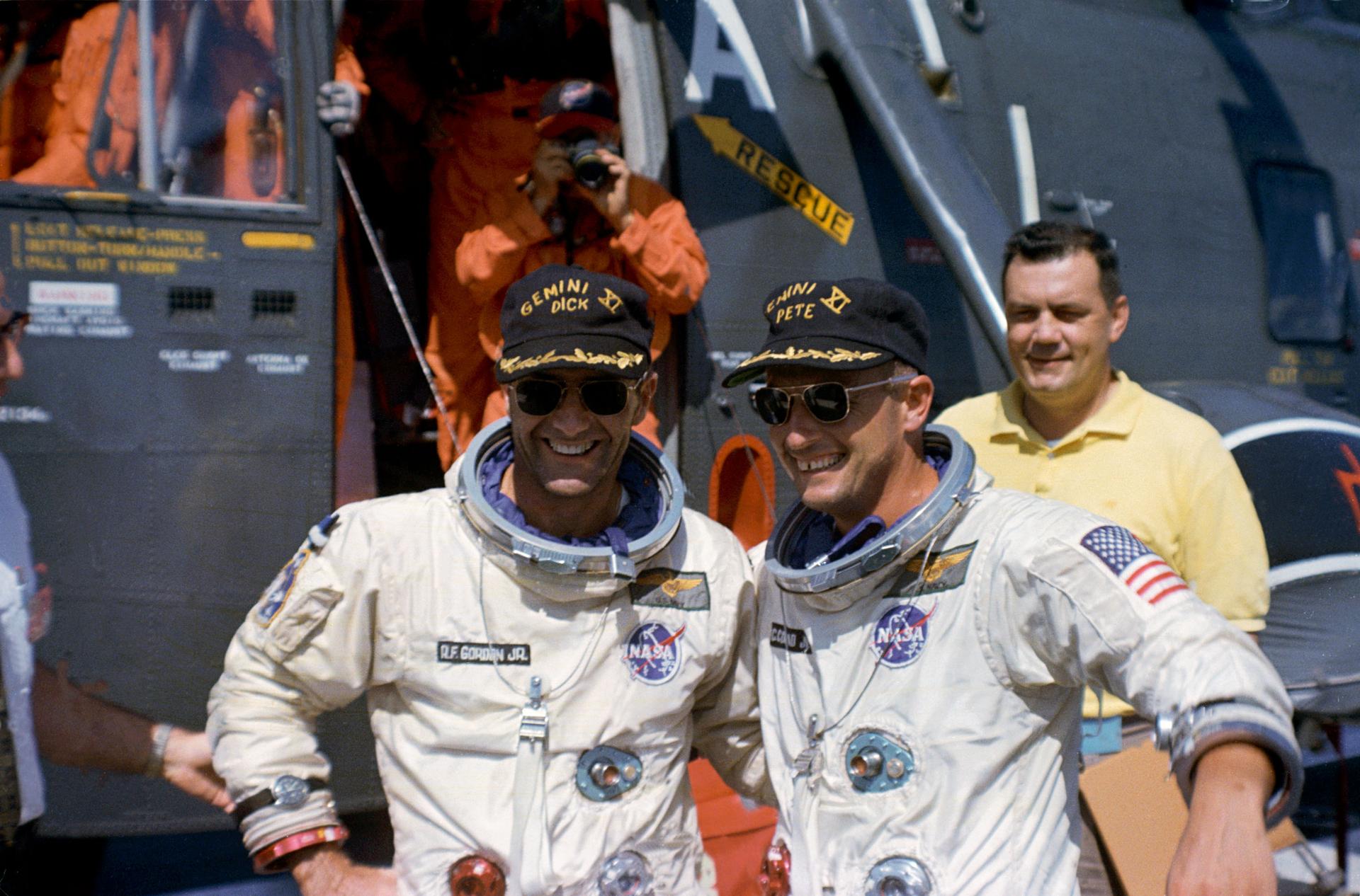 The Gemini-11 prime crew, astronauts Charles Conrad Jr. (right) and Richard F. Gordon Jr. pose in front of the recovery helicopter which brought them to the USS Guam.
