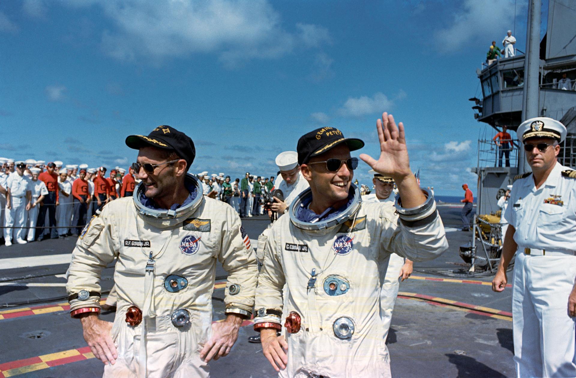 Pete Conrad and Dick Gordon smile and wave on the USS Guam after their Gemini 11 flight.