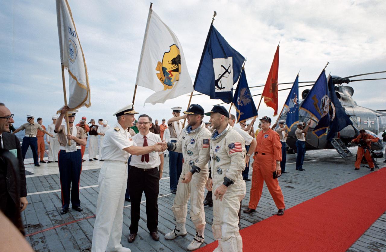 S66-59981 (15 Nov. 1966) --- Astronauts James A. Lovell Jr. (left), command pilot, and Edwin E. Aldrin Jr., pilot, receive official welcome as they arrive aboard the aircraft carrier USS Wasp. Gemini-12 splashed down in the Atlantic Ocean recovery area at 2:21 p.m. (EST), Nov. 15, 1966, to conclude a four-day mission in space. Photo credit: NASA