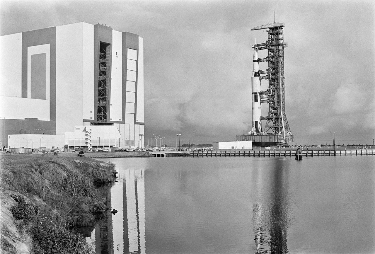 S68-49404 (9 Oct. 1968) --- The Apollo 8 (Spacecraft 103/Saturn 503) space vehicle on way from Kennedy Space Center's Vehicle Assembly Building to Pad A, Launch Complex 39. The Saturn V stack and its mobile launch tower are atop a huge crawler-transporter. (ground-level view, looking across water, with VAB on left)