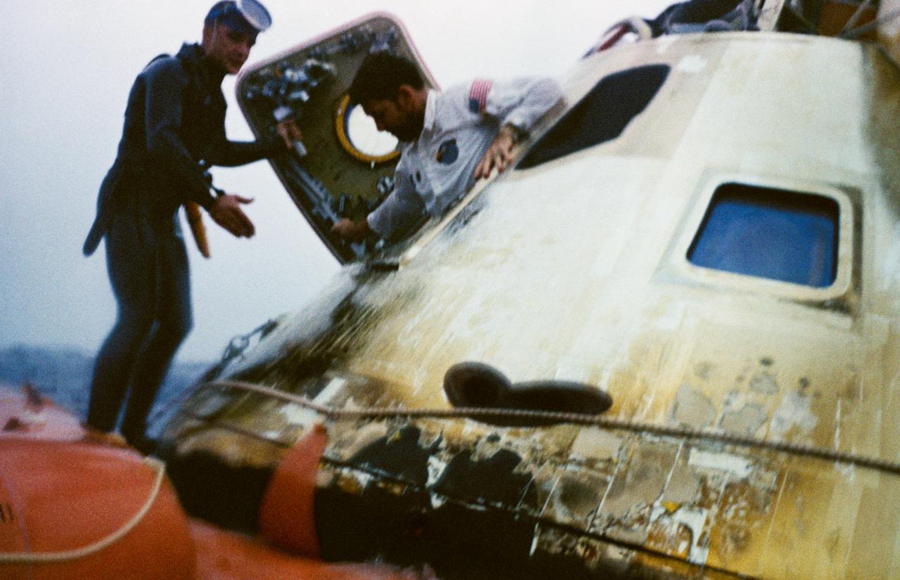 Astronaut Walter M. Schirra, Jr., Apollo 7 commander, egresses the spacecraft during recovery operations in the Atlantic. He is assisted by a member of the U.S. Navy frogman team. The Apollo 7 spacecraft splashed down at 7:11 a.m., October 22, 1968, approximately 200 nautical miles south-southwest of Bermuda.