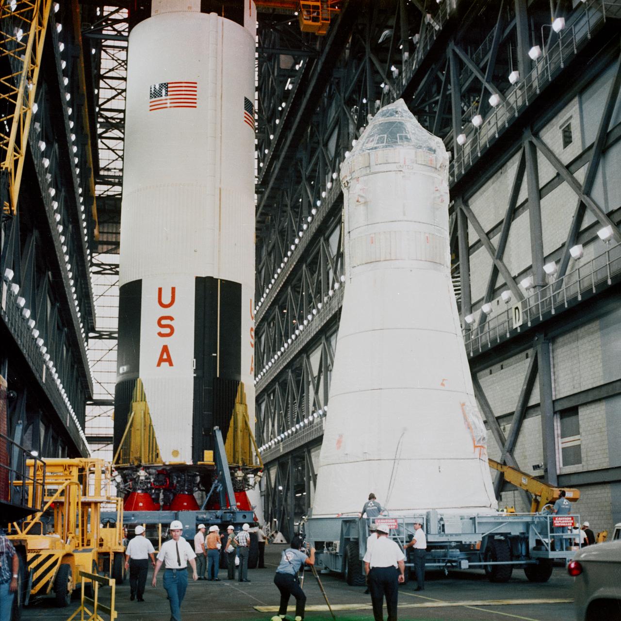 Apollo Spacecraft 104 Command/Service Module and Lunar Module 3 arrive at the Vehicle Assembly Building (VAB) for mating atop the Saturn 504 launch vehicle. The Saturn 504 stack is out of view. The Saturn V first (S-IC) stage in left background is scheduled for a later flight.