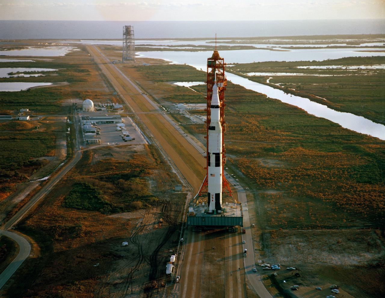 S69-17487 (3 Jan. 1969) --- Aerial view of the Apollo 9 (Spacecraft 104/Lunar Module 3/Saturn 504) space vehicle on the way from the Vehicle Assembly Building to Pad A, Launch Complex 39, Kennedy Space Center. The Saturn V stack and its mobile launch tower are atop a huge crawler-transporter. (view looking toward Pad A)