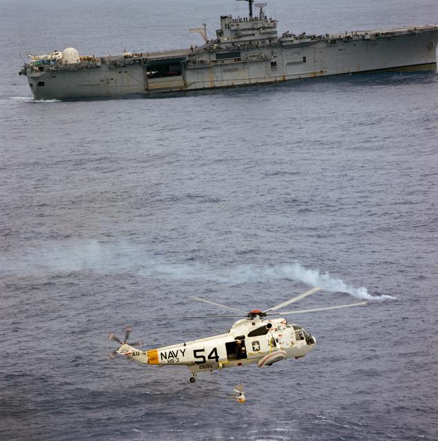 NASA image: Apollo 9 crewman in rescue net being hoisted up to helicopter