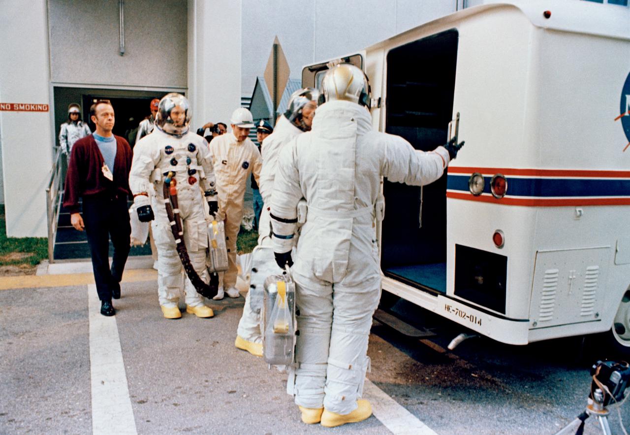 S69-25881 (3 March 1969) --- The Apollo 9 crew leaves the Kennedy Space Center's Manned Spacecraft Operations Building during the Apollo 9 prelaunch countdown. The crewman entered the special transfer van which transported them to their waiting spacecraft at Pad A, Launch Complex 39. Astronaut James A. McDivitt (back to camera) is the commander. McDivitt appears to be inviting astronaut David R. Scott, command module pilot, to step first into van. In background is astronaut Russell L. Schweickart, lunar module pilot. Walking along almost behind Schweickart is astronaut Alan B. Shepard Jr., chief, Astronaut Office, Manned Spacecraft Center. Apollo 9 was launched at 11 a.m. (EST), March 3, 1969, on a 10-day Earth-orbital mission.