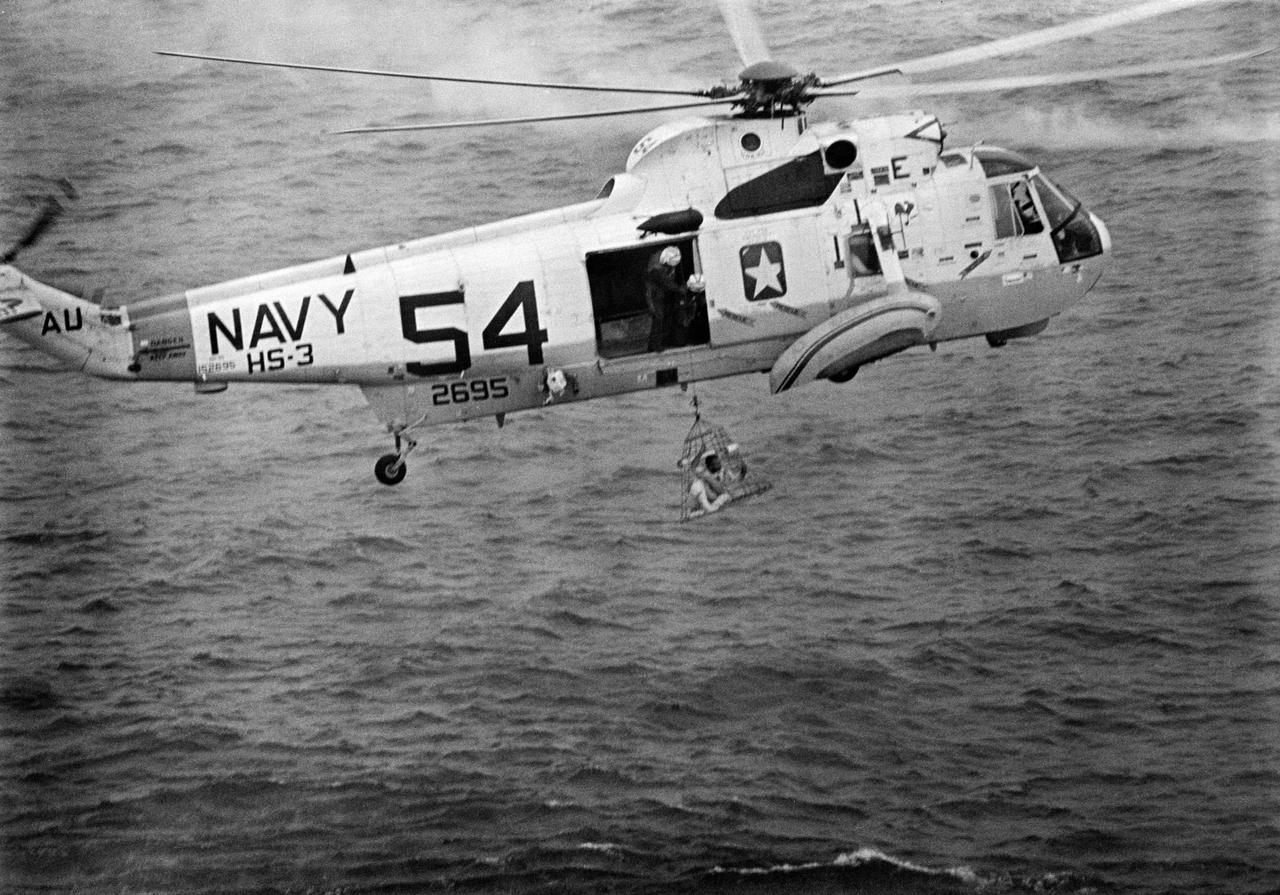 S69-27469 (13 March 1969) --- U.S. Navy helicopter crewmembers assist the Apollo 9 astronauts during recovery operations just after splashdown. Astronaut James A. McDivitt, mission commander, is in the Billy Pugh net about to aboard the helicopter. McDivitt was the third of the astronauts to egress the command module (out of frame). Also on the mission were astronauts David R. Scott, command module pilot; and Russell L. Schweickart, lunar module pilot. The three rehearsed in Earth orbit the transportation and docking maneuvers necessary to occur in lunar orbit in order for future crews to land on the moon's surface. Splashdown occurred at 12:00:53 p.m. (EST), March 13, 1969, only 4.5 nautical miles from the prime recovery ship, USS Guadalcanal, to conclude a successful 10-day mission.
