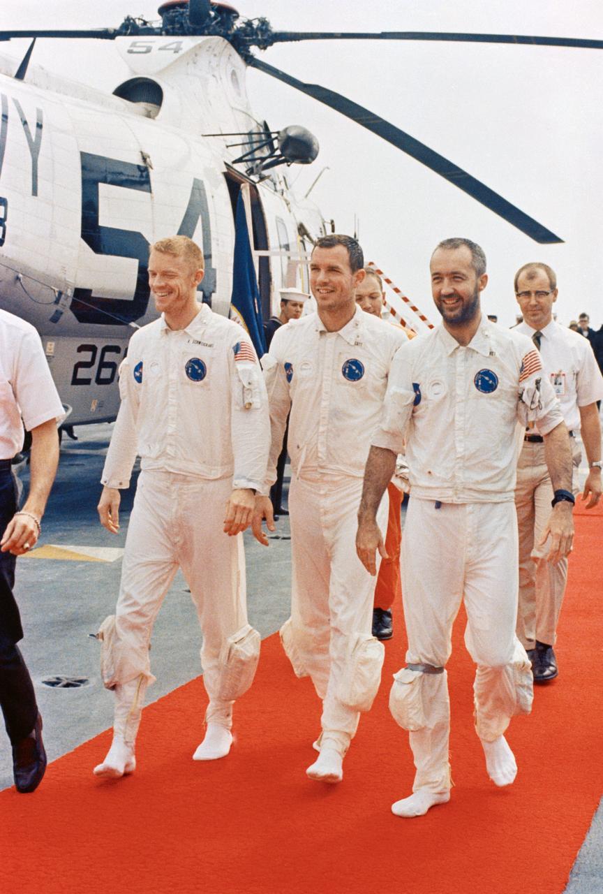 S69-27920 (13 March 1969) --- The Apollo 9 crew men walk on a red carpet after arriving aboard the prime recovery ship, USS Guadalcanal. Left to right, are astronauts Russell L. Schweickart, David R. Scott, and James A. McDivitt. They are walking from the recovery helicopter which picked them up from the splashdown area. Splashdown occurred at 12:00:53 p.m. (EST), March 13, 1969, only 4.5 nautical miles from the USS Guadalcanal to conclude a successful 10-day Earth-orbital space mission.
