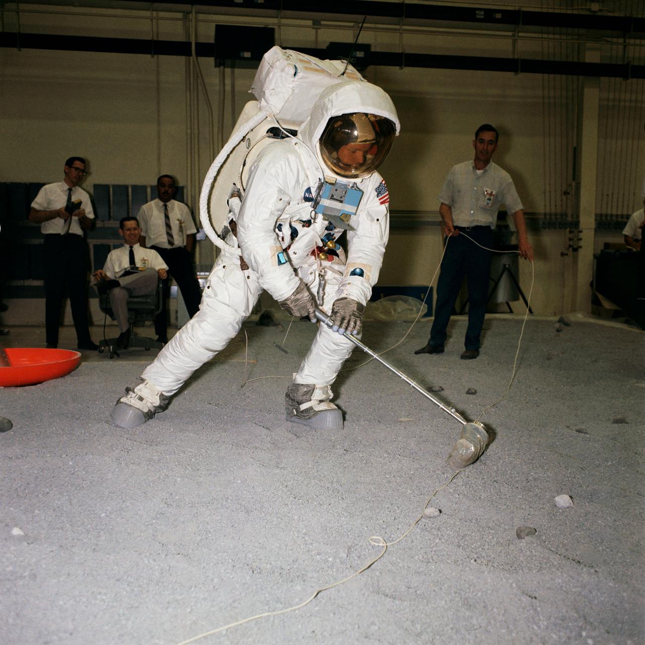 S69-31048 (18 April 1969) --- Suited astronaut Neil A. Armstrong, wearing an Extravehicular Mobility Unit (EMU), participates in lunar surface simulation training on April 18, 1969, in Building 9, Manned Spacecraft Center.  Armstrong is the prime crew commander of the Apollo 11 lunar landing mission. Here, he practices scooping up a lunar sample.