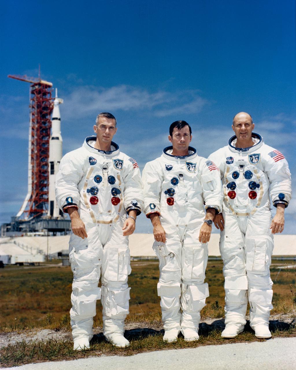S69-34329 (13 May 1969) --- The prime crew of the Apollo 10 lunar orbit mission sits for photograph while at the Kennedy Space Center for preflight training. Left to right are astronauts Eugene A. Cernan, lunar module pilot; John W. Young, command module pilot; and Thomas P. Stafford, commander. In the left background is the Apollo 10 space vehicle on Pad B, Launch Complex 39, Kennedy Space Center. The three crewmen had just completed a Countdown Demonstration Test exercise.