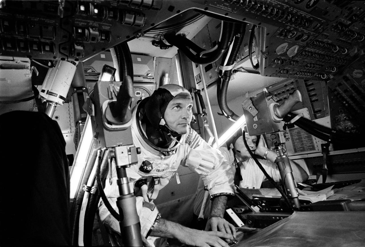 Apollo 11 Command Module (CM) pilot Mike Collins practicing docking hatch removal from CM turned in simulator.