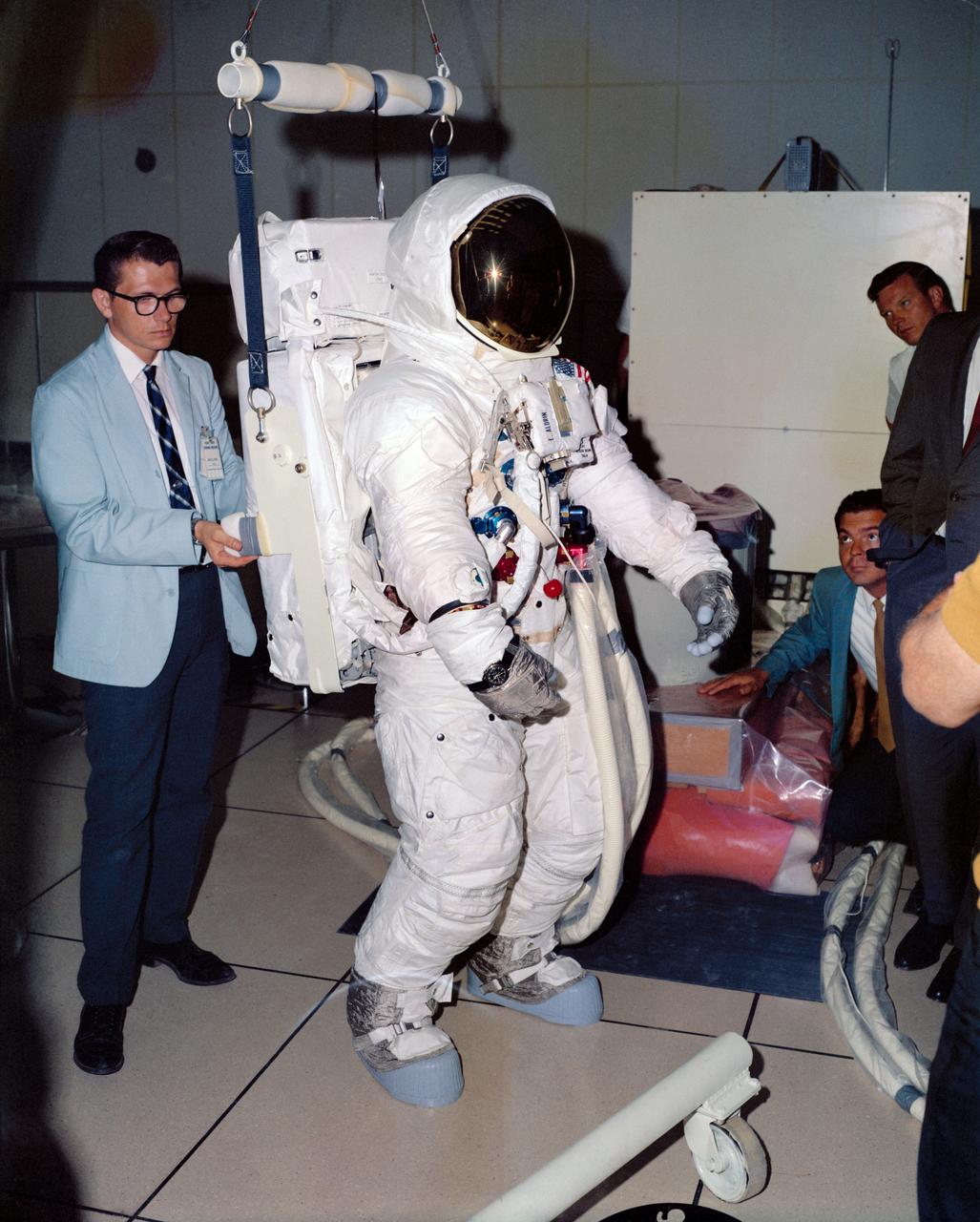 Astronaut Edwin E. Aldrin Jr., wearing an Extravehicular Mobility Unit (EMU), verifies fit of the Portable Life Support System (PLSS) strap length during lunar surface training at the Kennedy Space Center. Aldrin is the prime crew lunar module pilot of the Apollo 11 lunar landing mission. Aldrin's PLSS backpack is attached to a lunar weight simulator.