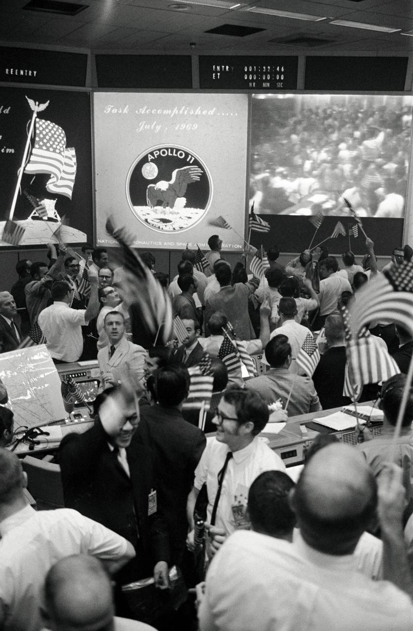 S69-40023 (24 July 1969) --- Overall view of the Mission Operations Control Room (MOCR) in the Mission Control Center (MCC), Building 30, Manned Spacecraft Center (MSC), showing the flight controllers celebrating the successful conclusion of the Apollo 11 lunar landing mission.