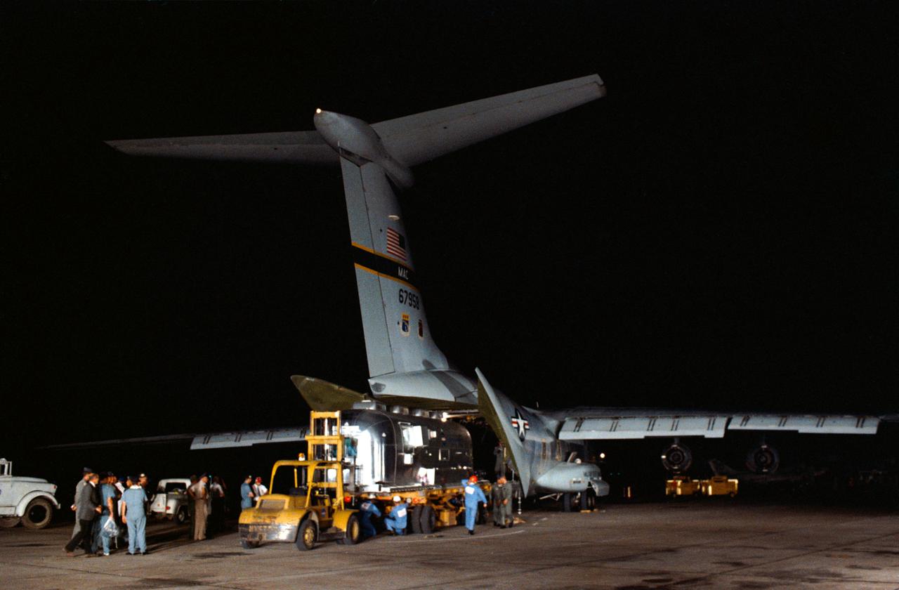 S69-40132 (27 July 1969) --- A Mobile Quarantine Facility (MQF), with the three Apollo 11 crewmembers inside, is unloaded from a United States Air Force C-141 transport at Ellington Air Force Base very early Sunday after a flight from Hawaii. A large crowd was present to welcome astronauts Neil A. Armstrong, Michael Collins, and Edwin E. Aldrin Jr. back to Houston following their historic lunar landing mission. The crew remained in the MQF until they arrived at the Crew Reception Area of the Lunar Receiving Laboratory (LRL) at the Manned Spacecraft Center (MSC). The crew will be released from quarantine on Aug. 11, 1969.