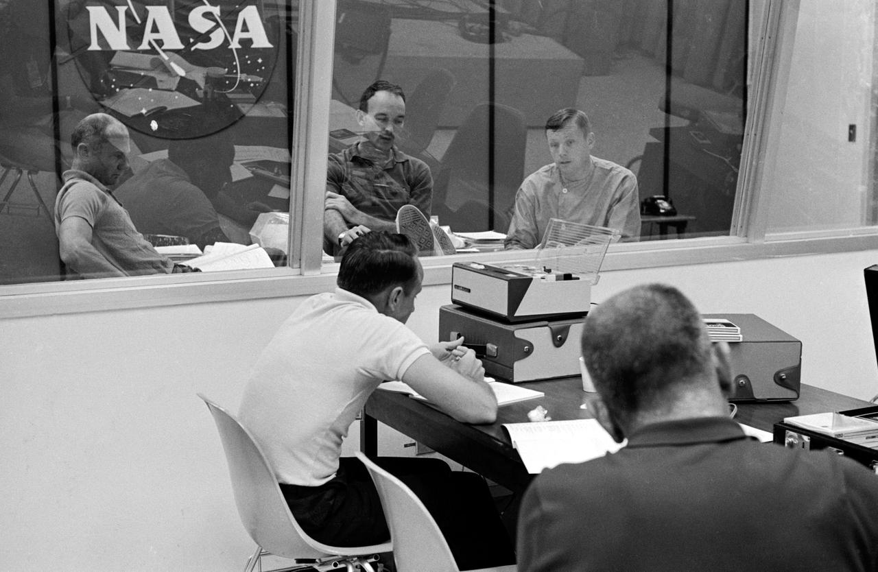 S69-40209 (27 July 1969) --- The crewmen of the Apollo 11 lunar landing mission go through their post flight debriefing session on Sunday, July 27, 1969. Left to right, are astronauts Edwin E. Aldrin Jr., lunar module pilot; Michael Collins, command module pilot; and Neil A. Armstrong, commander. They are seated in the debriefing room of the Crew Reception Area of the Lunar Receiving Laboratory at the Manned Spacecraft Center (MSC). In the foreground are Donald K. Slayton (right), MSC Director of Flight Crew Operations; and Lloyd Reeder, training coordinator.