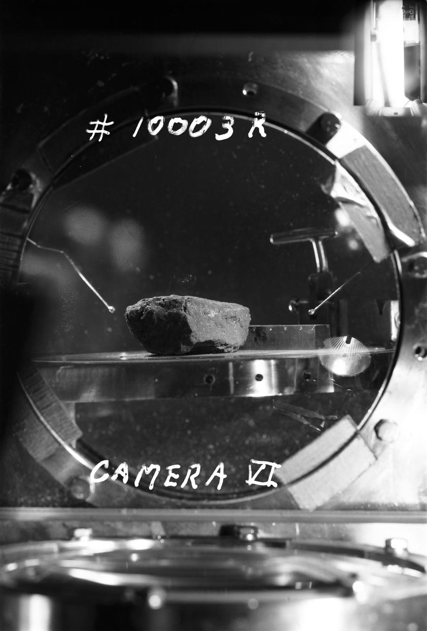 S69-45009 (27 July 1969) --- This is the first lunar sample that was photographed in detail in the Lunar Receiving Laboratory (LRL) at the Manned Spacecraft Center (MSC).  The photograph shows a granular, fine-grained, mafic (iron magnesium rich) rock.  At this early stage of the examination, this rock appears similar to several igneous rock types found on Earth.  The scale is printed backwards due to the photographic configuration in the Vacuum Chamber.  The sample number is 10003.  This rock was among the samples collected by astronauts Neil A. Armstrong and Edwin E. Aldrin Jr. during their lunar surface extravehicular activity (EVA) on July 20, 1969.